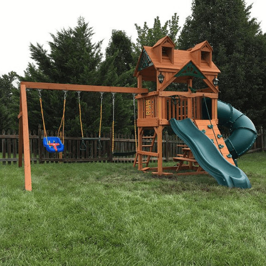 mountaineer swing set with treehouse rood in the backyard